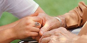 immagine che ritrae mani di persona anziana che si appoggia a supporto con l'aiuto di un'altra persona