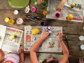 tavolo con colori e mani di adolescenti che colorano oggetti