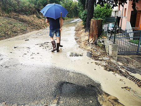 Uomo che cammina nel fango con ombrello