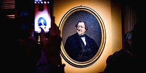 Persona con in mano un cellulare mentre fotografa il ritratto di Gioacchino Rossini