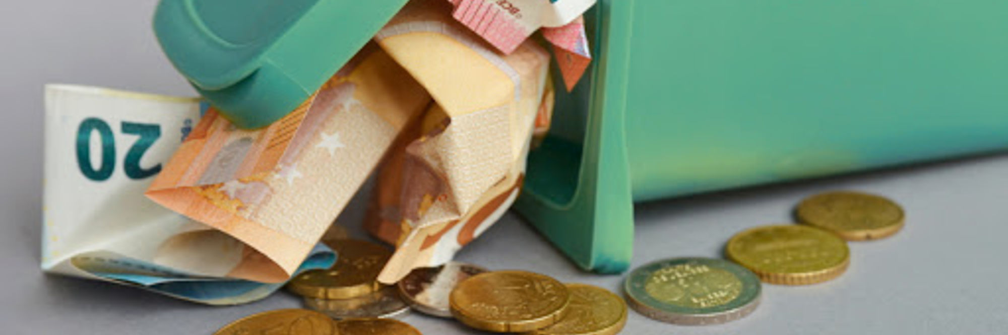 Soldi in carta e spiccioli che escono da un bidoncino verde