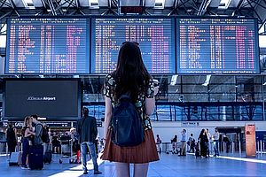 ragazza di spalle che guarda tabellone aereoporto