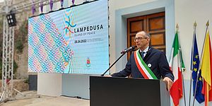 Sindaco con scritta Lampedusa alle spalle