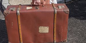 Immagine di valigia tenuta da una mano maschile