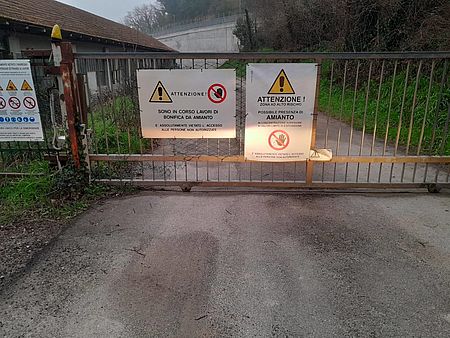 Muraglia, iniziata la bonifica dall’amianto dell’ex fabbrica Carloni. Biancani e Conti: «Risultato importante per la tutela della salute dei lavoratori e dei residenti» Cancello con cartelli "bonifica amianto"