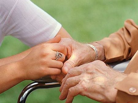 immagine che ritrae mani di persona anziana che si appoggia a supporto con l'aiuto di un'altra persona