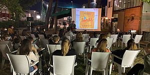 Ragazzi seduti in parco che stanno guardando il maxi schermo