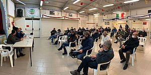 Persone sedute distanziate al centro sociale Asilo