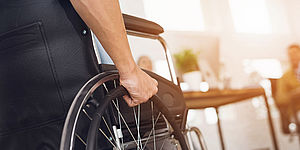 Mani che spingono sedia a rotelle