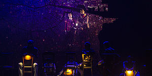 Persone sedute in sedie nel palcoscenico con luce molto tenue