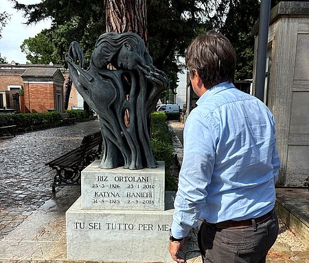 Biancani davanti alla tomba di Riz Ortolani