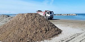 Camion con montagna di sabbia in spiaggia