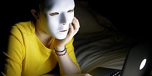 paticolare immagine locandina raffigurante ragazza davanti a un computer con maschera in volto