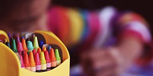 scatola di colori a cera e bambino che disegna